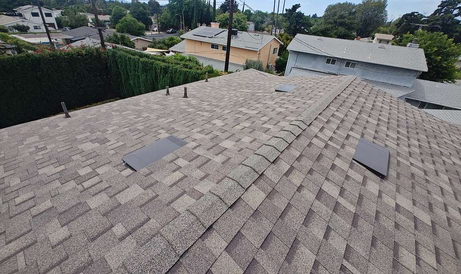 Finished brown-gray shingle roof with vents and ridge details.