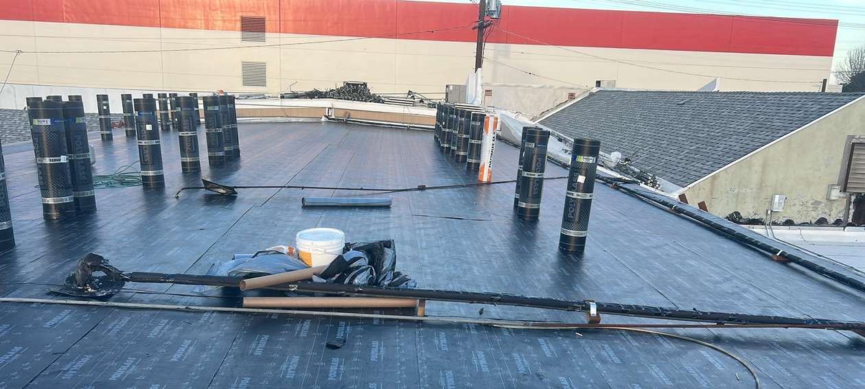 Broad commercial low-slope roof during active roofing work.