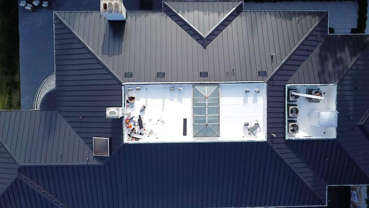 Aerial view of a finished standing-seam metal roof around a low-slope center.