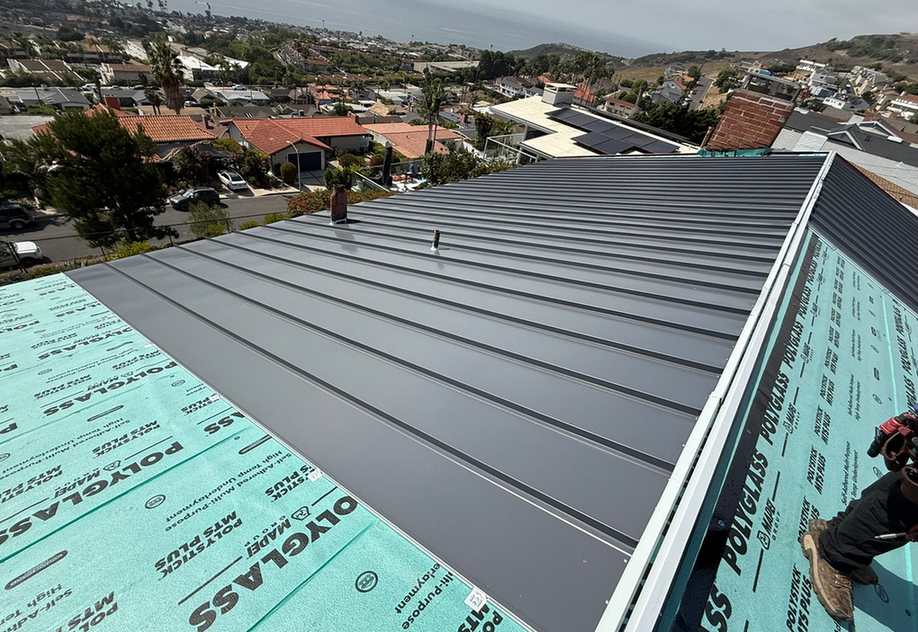 Broad standing-seam metal roof plane during installation.