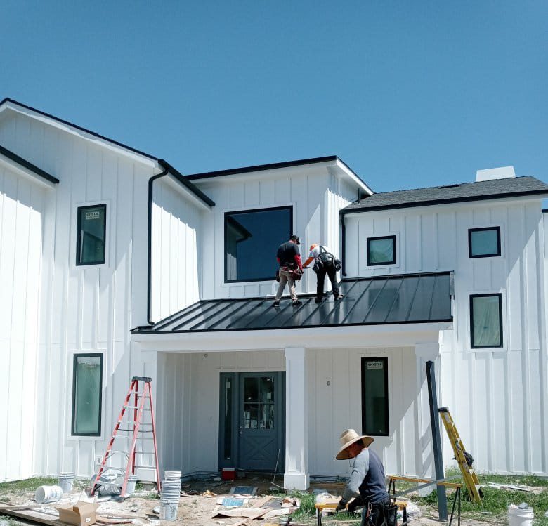 Roofers installing metal panels on a residence.