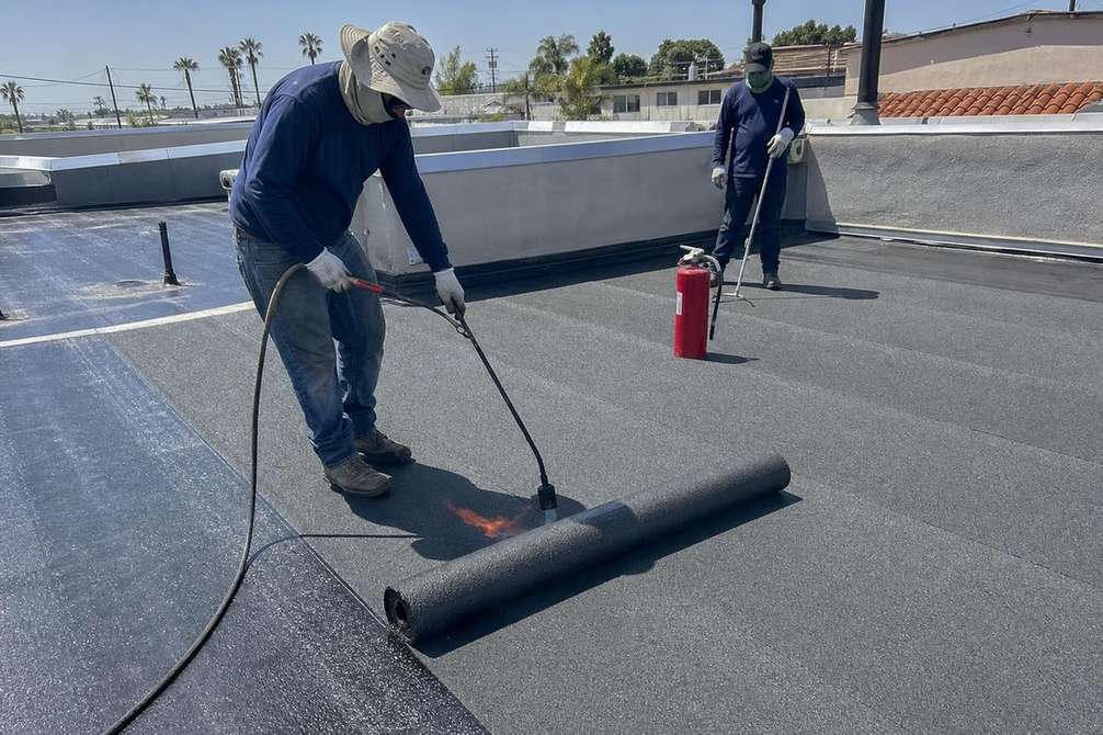 Roofers working across a low-slope roofing surface.