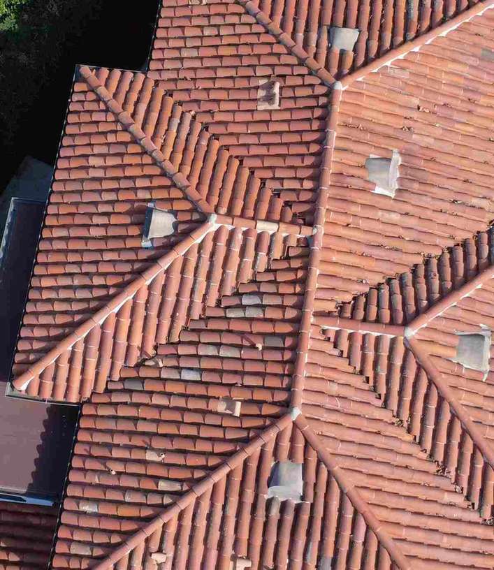 A weathered red barrel-tile roof with several hips.